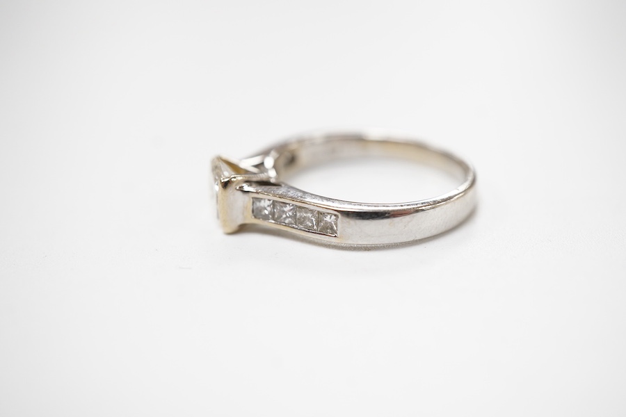 A diamond ring, set with a princess-cut diamond weighing approximately 0.40 carats, to shoulders channel-set with smaller princess-cut diamonds totalling approximately 0.40 carats, mounted in 18ct white gold, size K1/2,